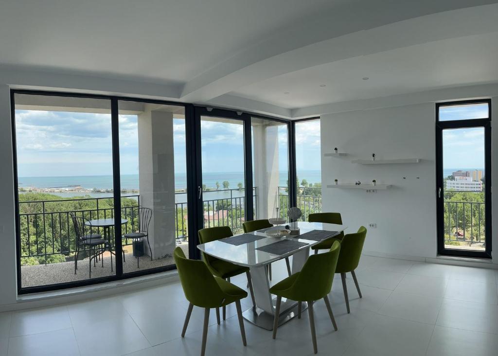 a dining room with a table and chairs and windows at Panoramic Sea View 3 rooms Apartment in Neptun. in Neptun