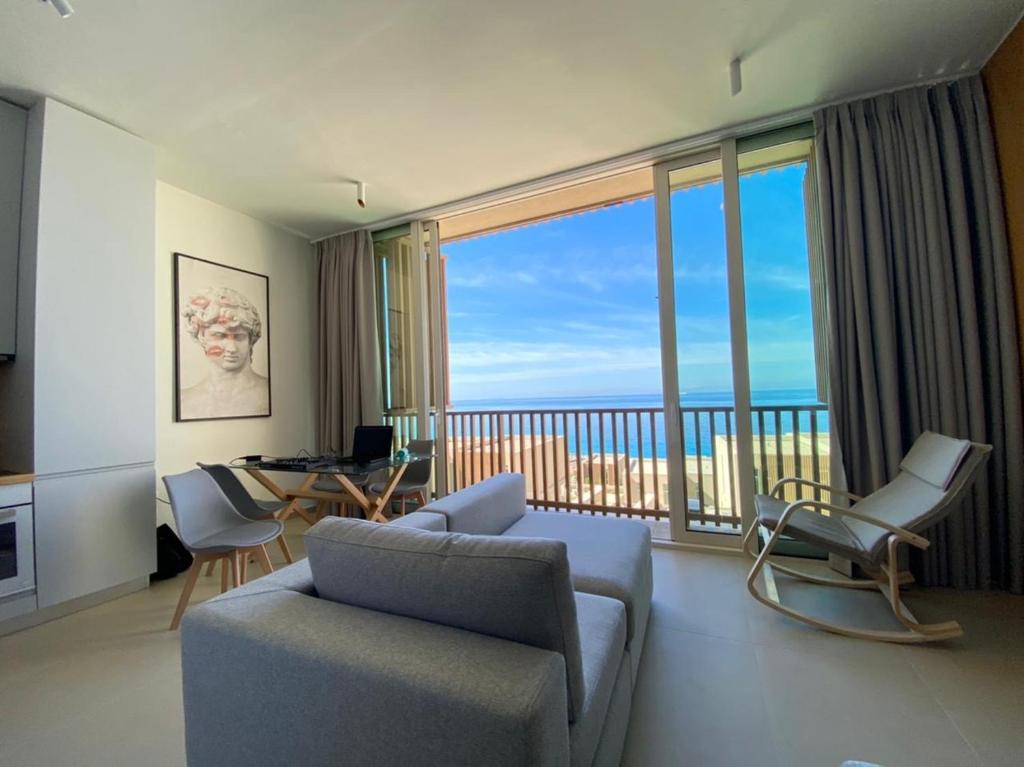 sala de estar con sofá y sillas y balcón en Heaven Residence - Green Coast Resort, Palasë en Llogara