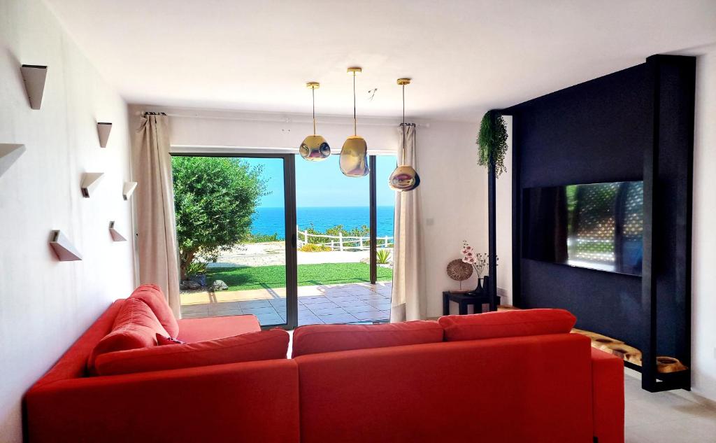 a red couch in a living room with a view of the ocean at Seafront apartment with private garden in Saint Amvrosios