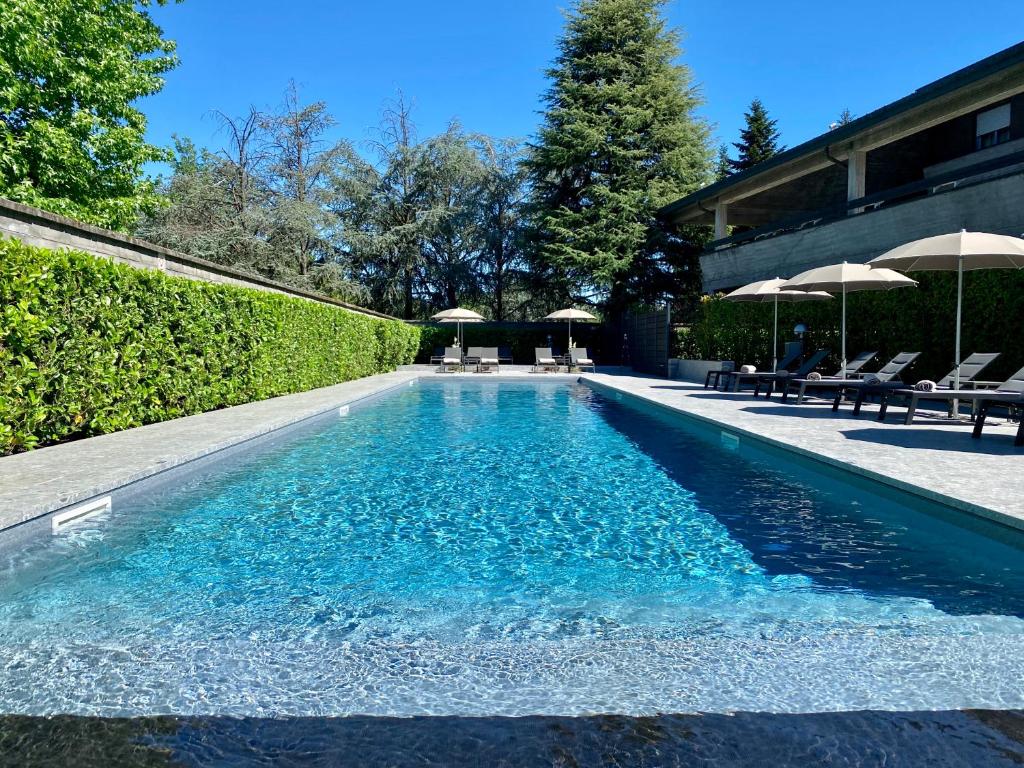 - une piscine dans une cour avec des chaises et des parasols dans l'établissement Peralba Autohotel, à Cornaredo