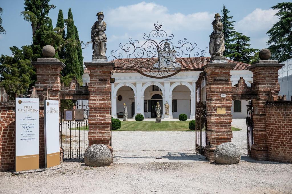 uma entrada para um edifício com um portão com estátuas em Le Camere di Villa Cà Zenobio em Treviso