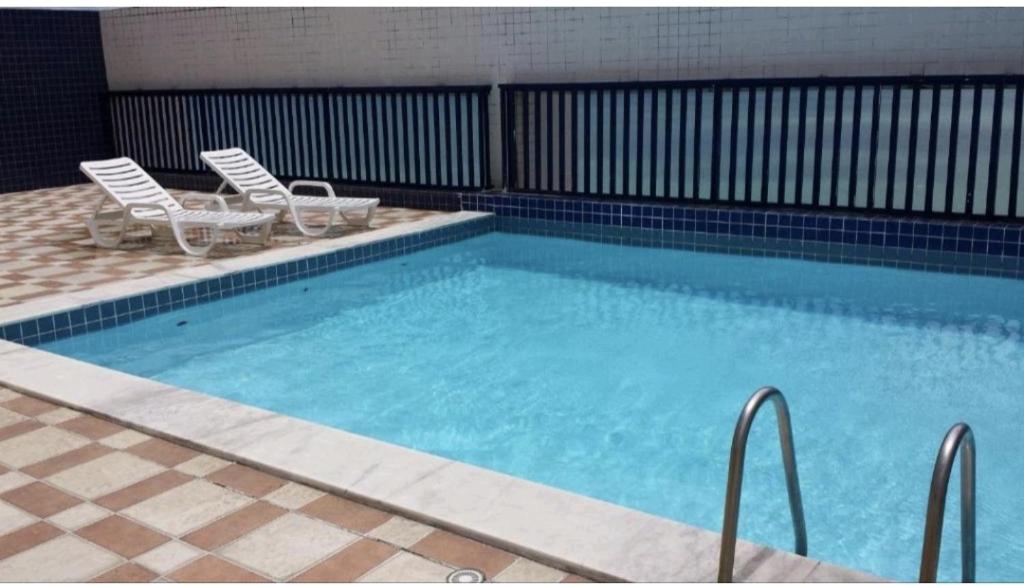 a large swimming pool with two chairs at Studio Everest Flat vista mar in Recife