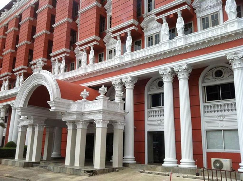 a red and white building with white columns at Suda Palace in Bangkok