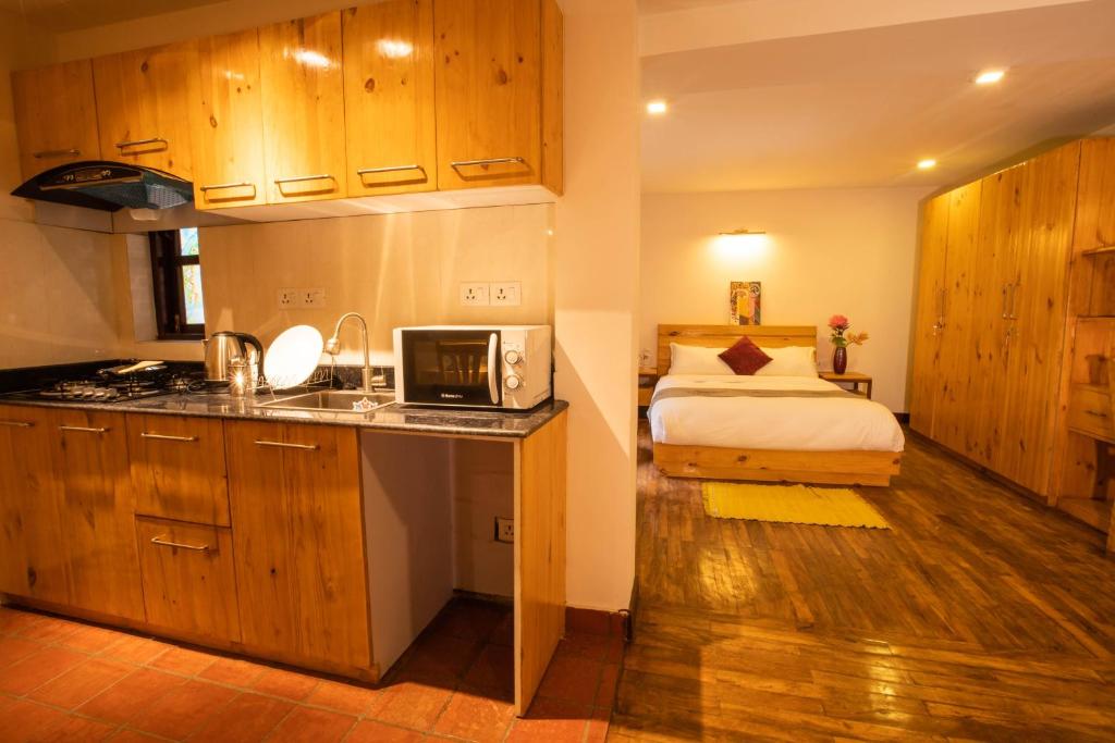 a bedroom with a bed and a kitchen with a microwave at Patan Wittys hotel in Pātan