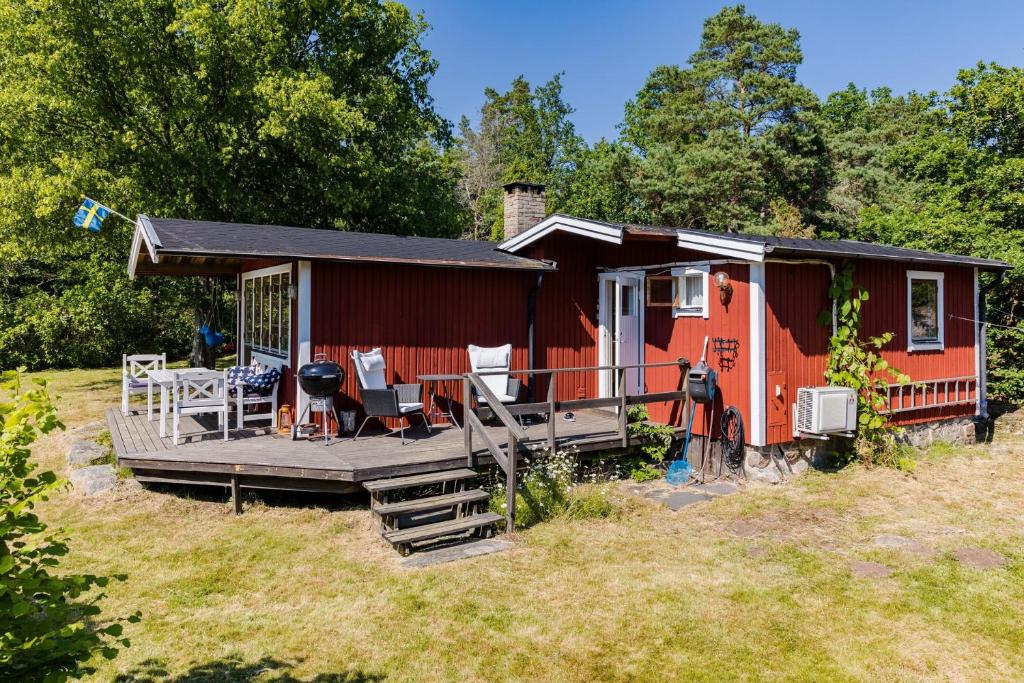 una casita roja pequeña con porche y terraza en Nice and family friendly holiday home in Trensum Karlshamn, en Trensum