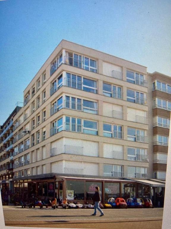 a man walking in front of a large building at Appartement vue sur mer - Splendide localisation! in Sint-Idesbald