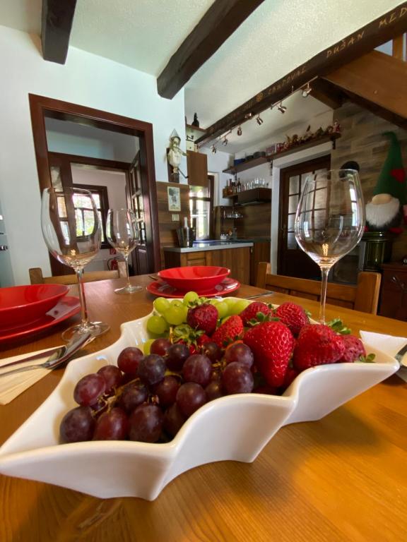 a plate of fruit on a table with wine glasses at Chalupa MATEJKO in Liptovský Mikuláš