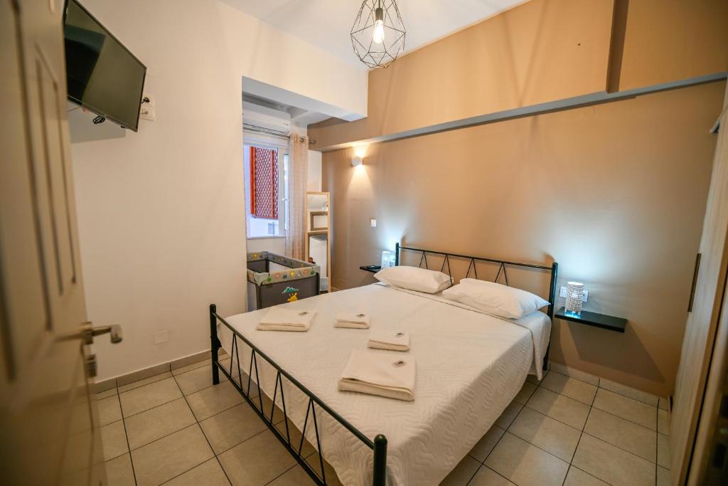 a bedroom with a bed with white sheets and a tv at Artemis No.2 Apartment in Kissamos