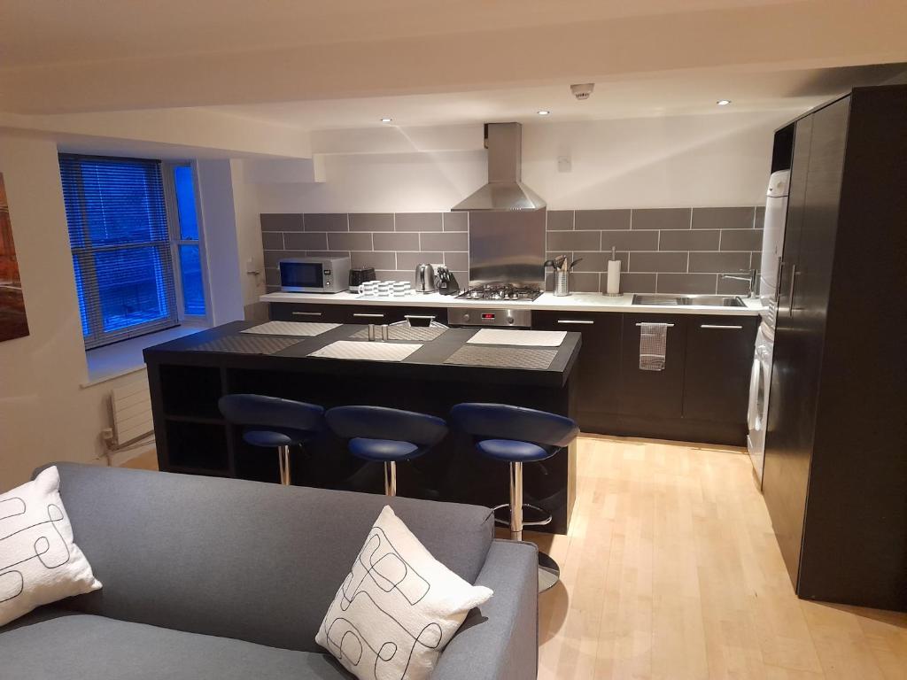 a kitchen with a black island in a kitchen with a couch at North Laine Deluxe Apartment sleeps 6 in Brighton & Hove