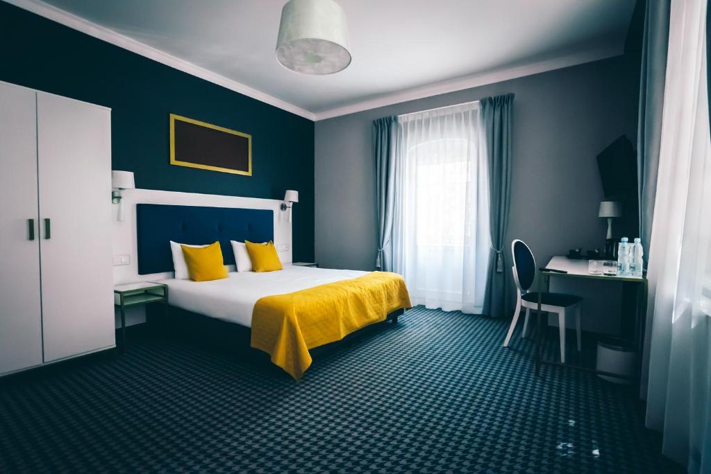 sypialnia z łóżkiem z żółtą pościelą i biurkiem w obiekcie Villa Art Novis we Wrocławiu
