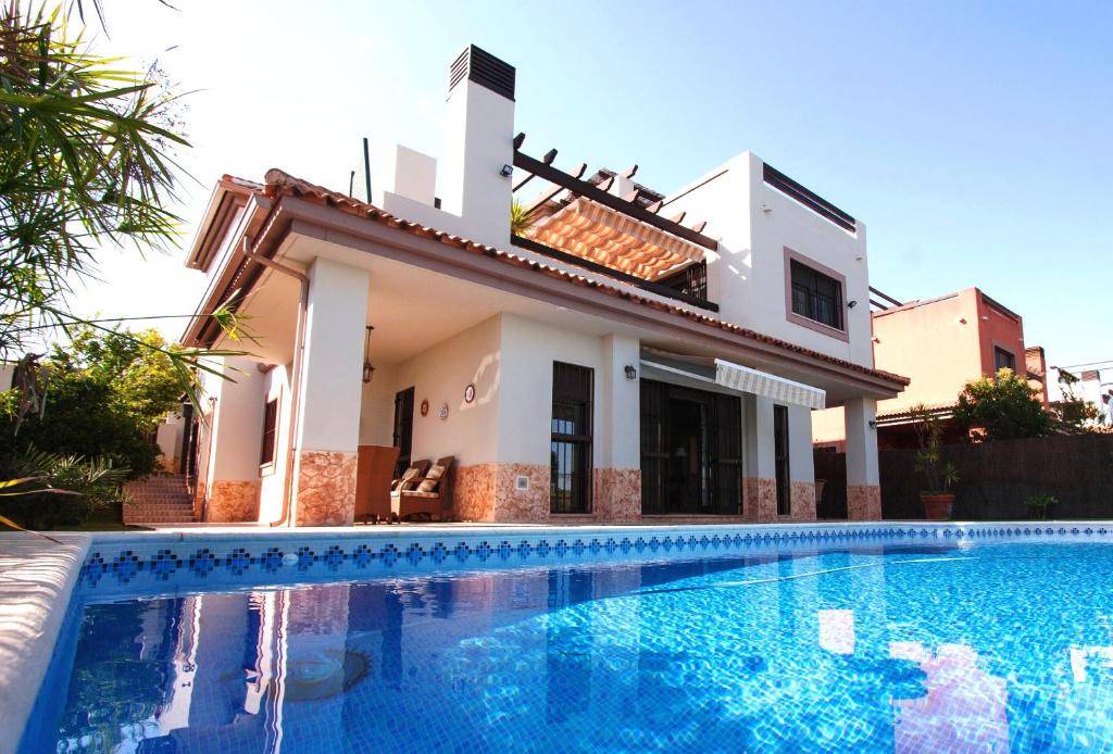 a villa with a swimming pool in front of a house at Casa Do Lago in Guillena