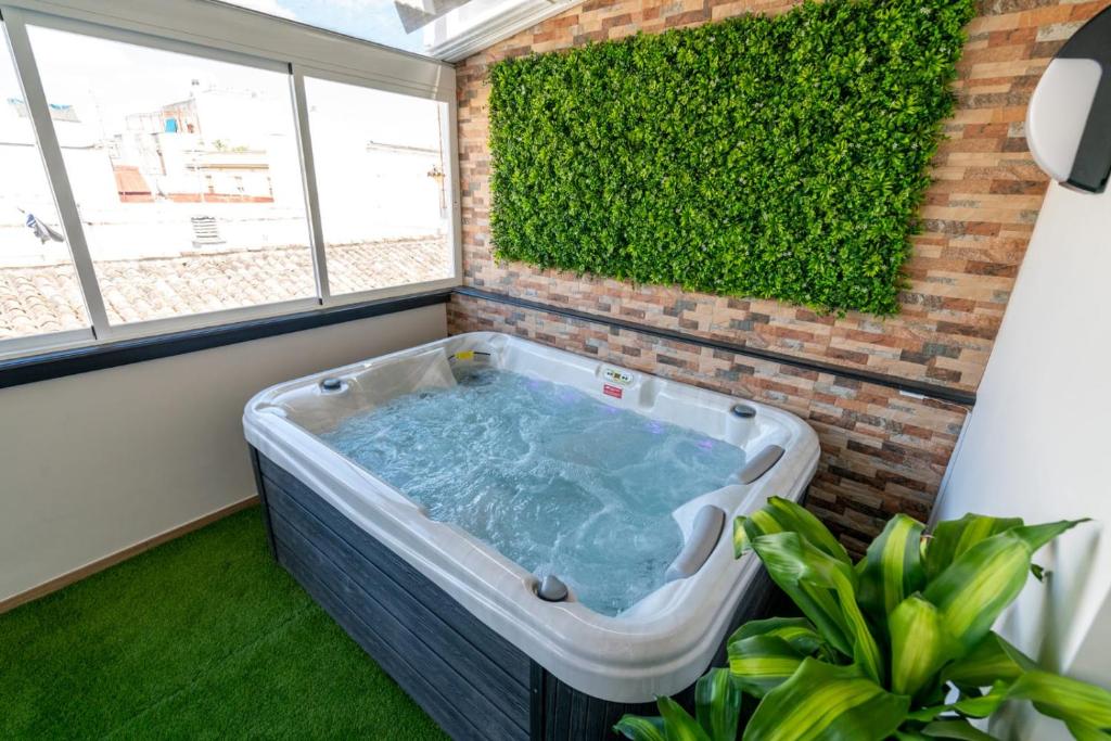 uma banheira de hidromassagem num quarto com uma cerca verde em Cabildo Spa 1 em Sanlúcar de Barrameda