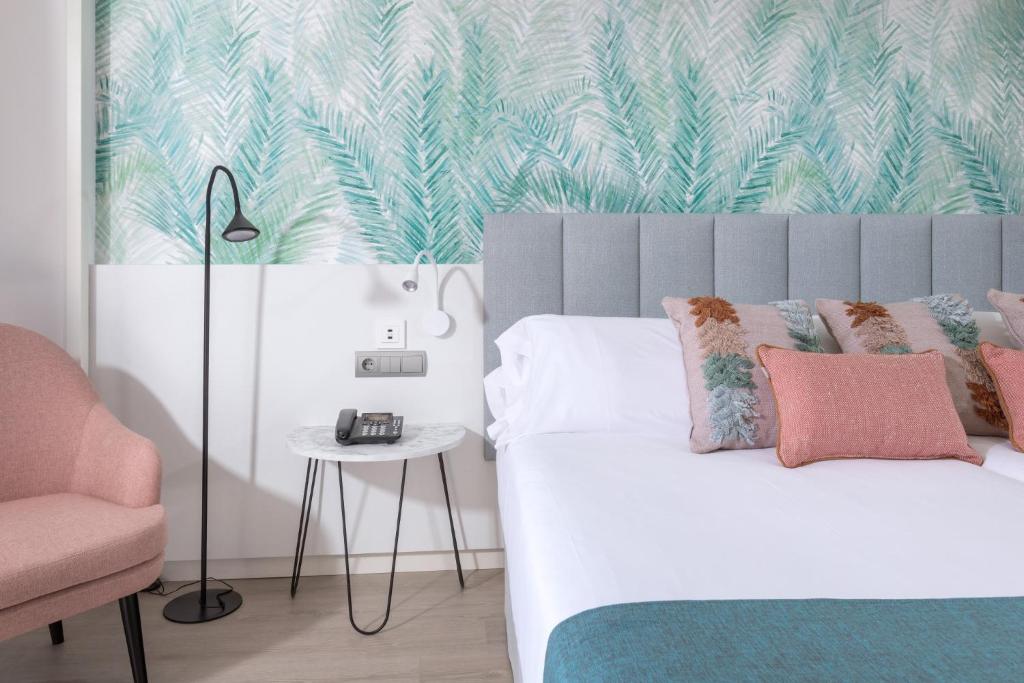 a bedroom with a bed and a pink chair at Hotel Cristina by Tigotan Las Palmas - Adults Only in Las Palmas de Gran Canaria