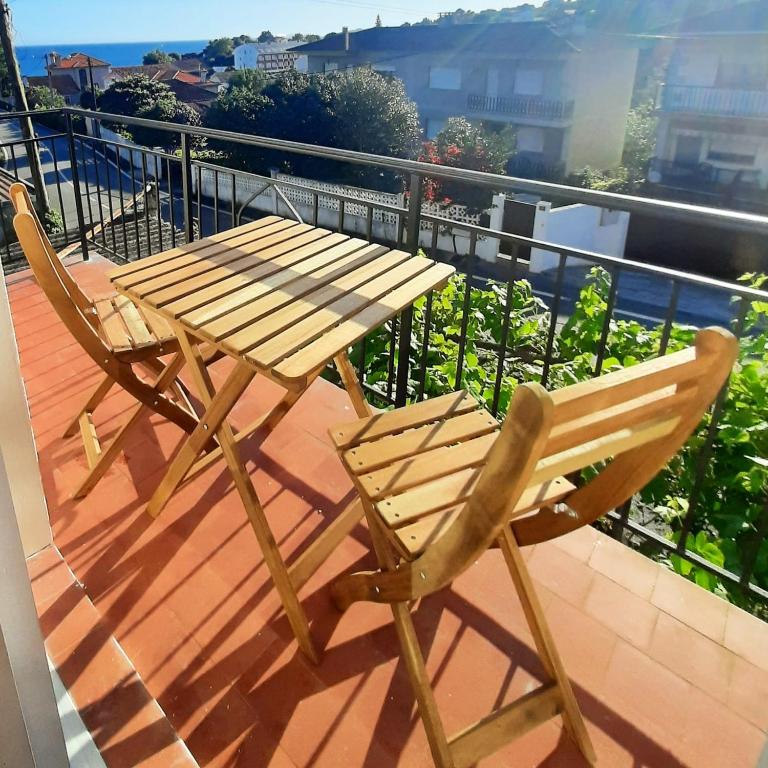 a wooden table and chair sitting on a balcony at Apartamentos Mar de Nanín in Sanxenxo