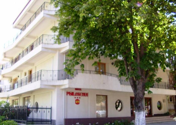 a white building with a tree in front of it at HOTEL PHILOXENIA in Eforie Nord