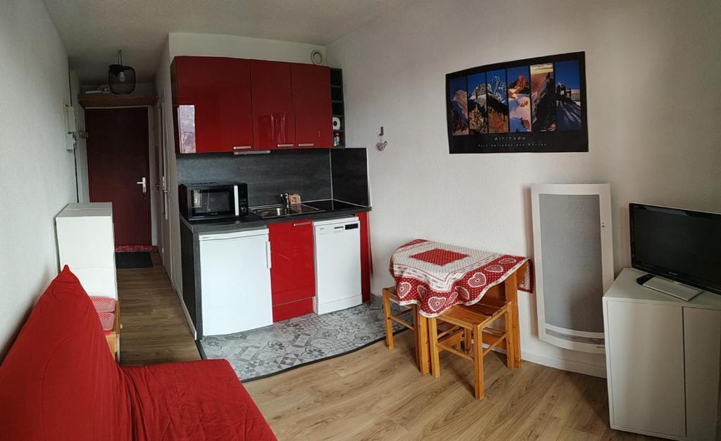 une petite cuisine avec des placards rouges et blancs et une télévision dans l'établissement Appartement 4pers Rénové Pied des Pistes - Balcon Vue Montagne, à Puy-Saint-Vincent
