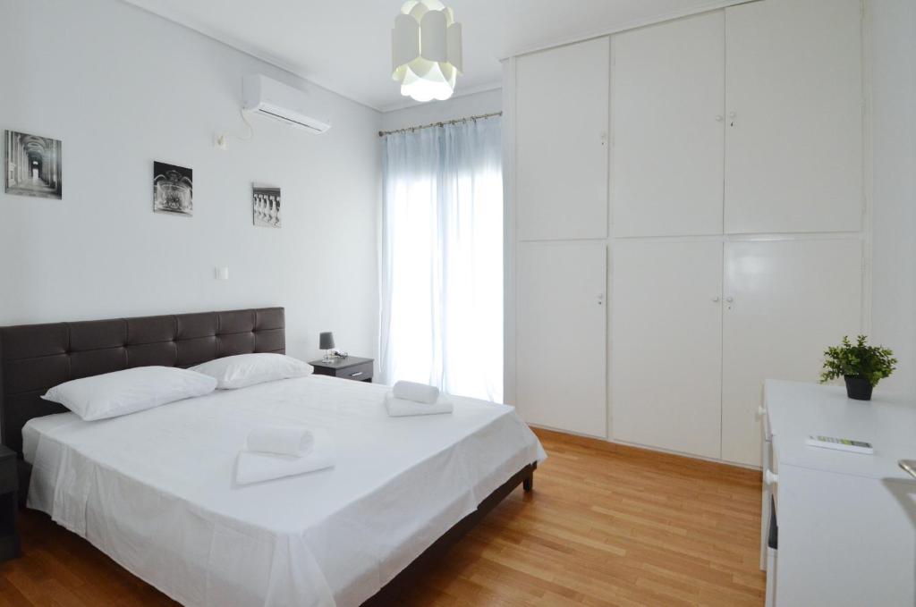 a white bedroom with a large bed and a window at A spacious minimal apatment at Chalandri in Athens