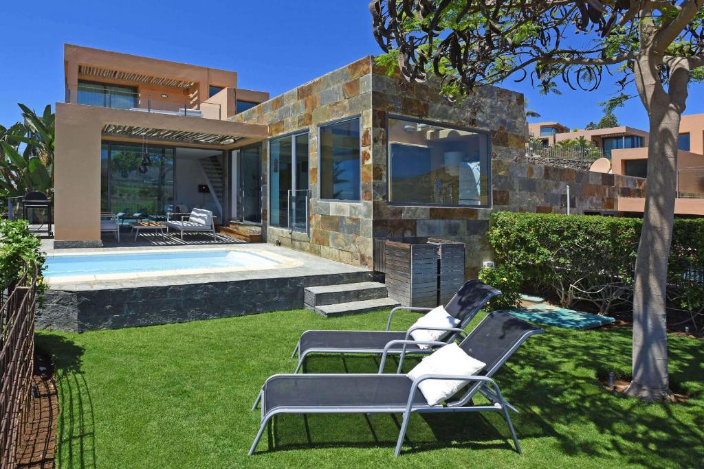 a villa with a swimming pool and two lawn chairs at Salobre Los Lagos 26 in Maspalomas