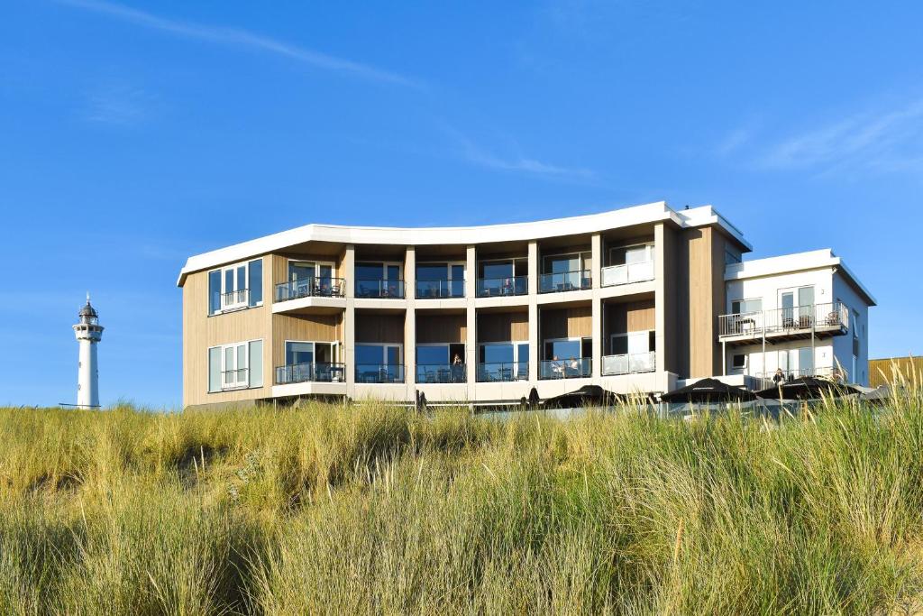 un bâtiment au sommet d'une colline avec de l'herbe dans l'établissement Lido Zeezicht appartementen, à Egmond aan Zee