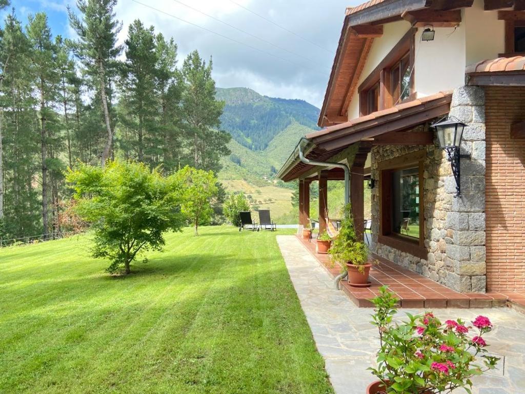 uma casa com um jardim verde com um campo de relva em Villa Almudena em Potes