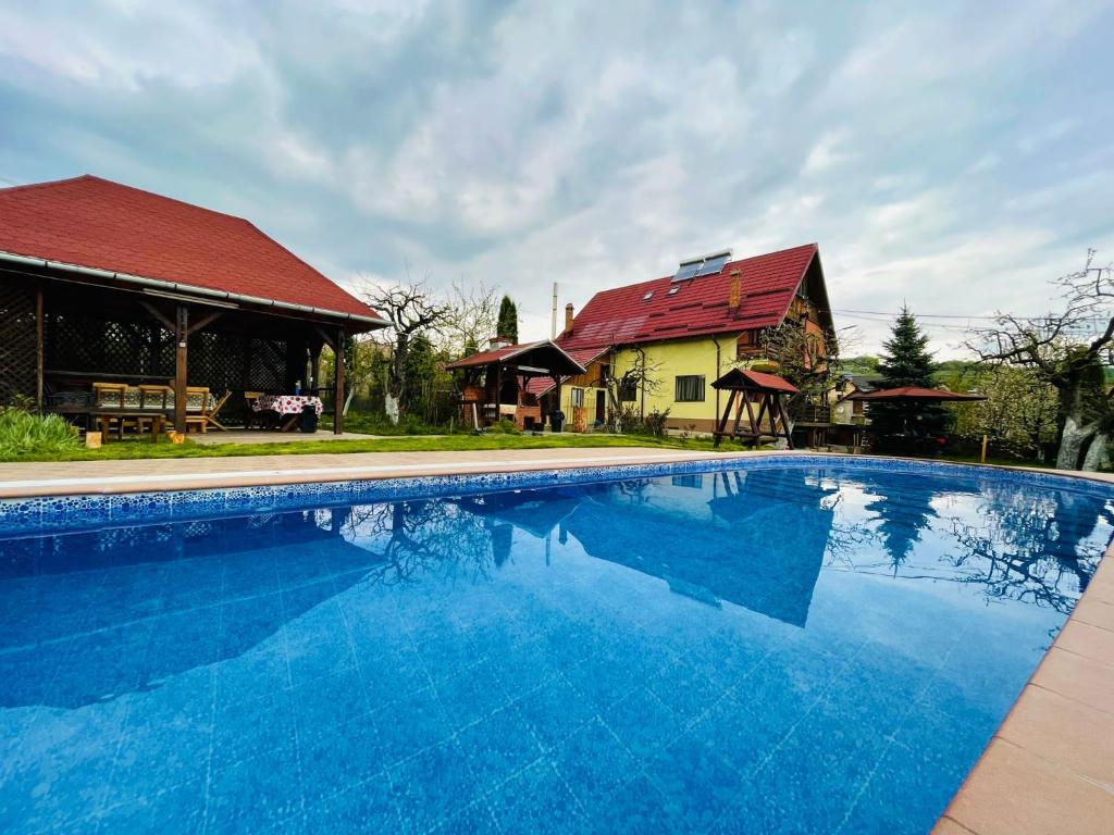 a large blue swimming pool in front of a house at Pensiunea Enothera in Văleni- Dîmboviţa