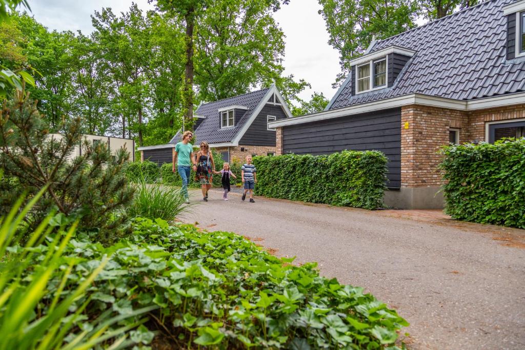 a family walking down a driveway in front of a house at EuroParcs Maasduinen in Belfeld
