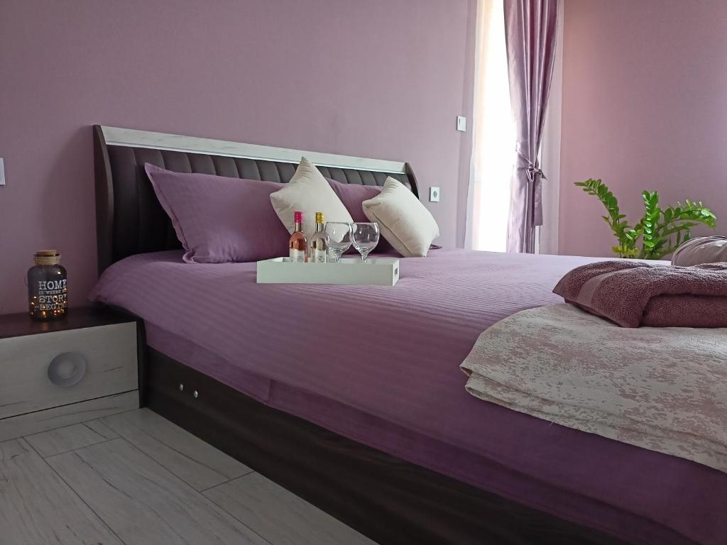 a purple bed with a tray with wine glasses on it at Стоянови in Ruse