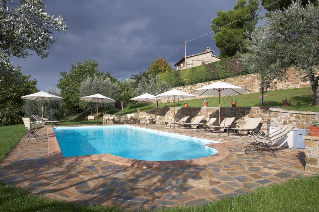 a swimming pool with chairs and umbrellas in a yard at Casale Favilluta in Petrignano