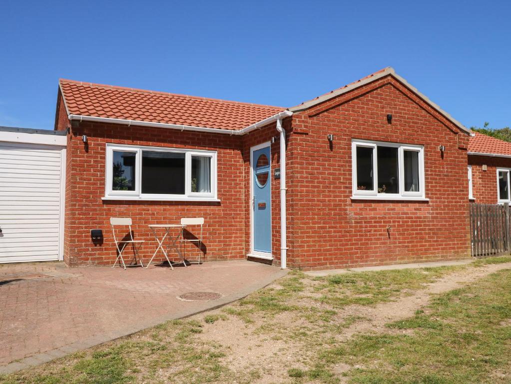 a brick house with a blue door and a patio at Samphire in Skegness
