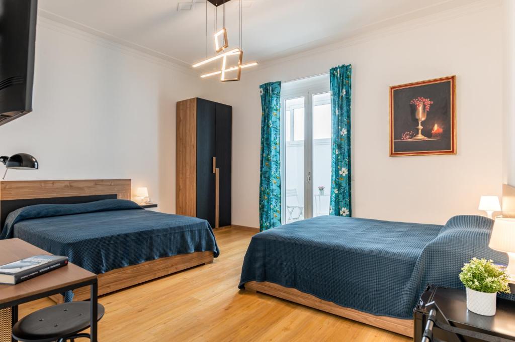 Un dormitorio con dos camas y una mesa. en Aurora Rooms, en Catania