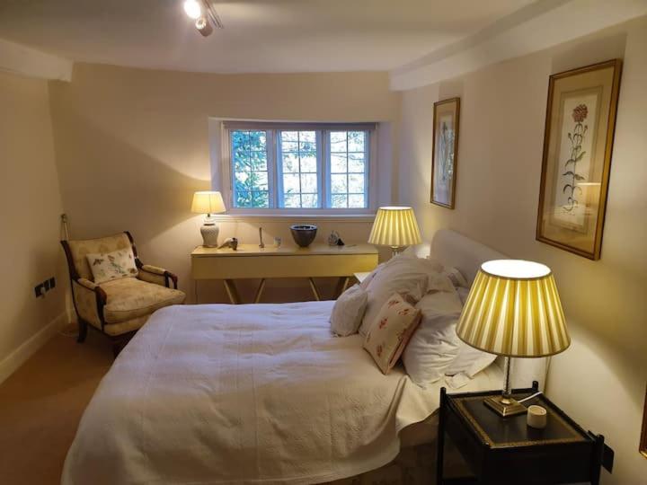 a bedroom with a bed and a desk and two lamps at Church Farm House in Cirencester