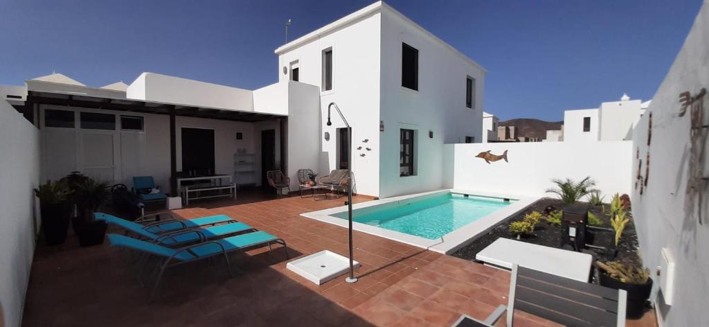 eine Villa mit einem Pool und einem Haus in der Unterkunft Splendid Casa Papagayo, heated pool, roofterrace with views and Wifi in Playa Blanca