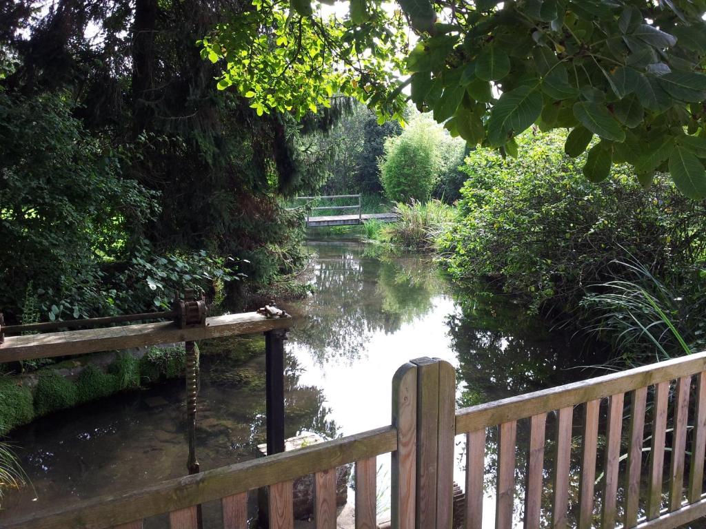 a river with a wooden fence next to a bridge at Gite de l'Ancien Moulin in Valmont