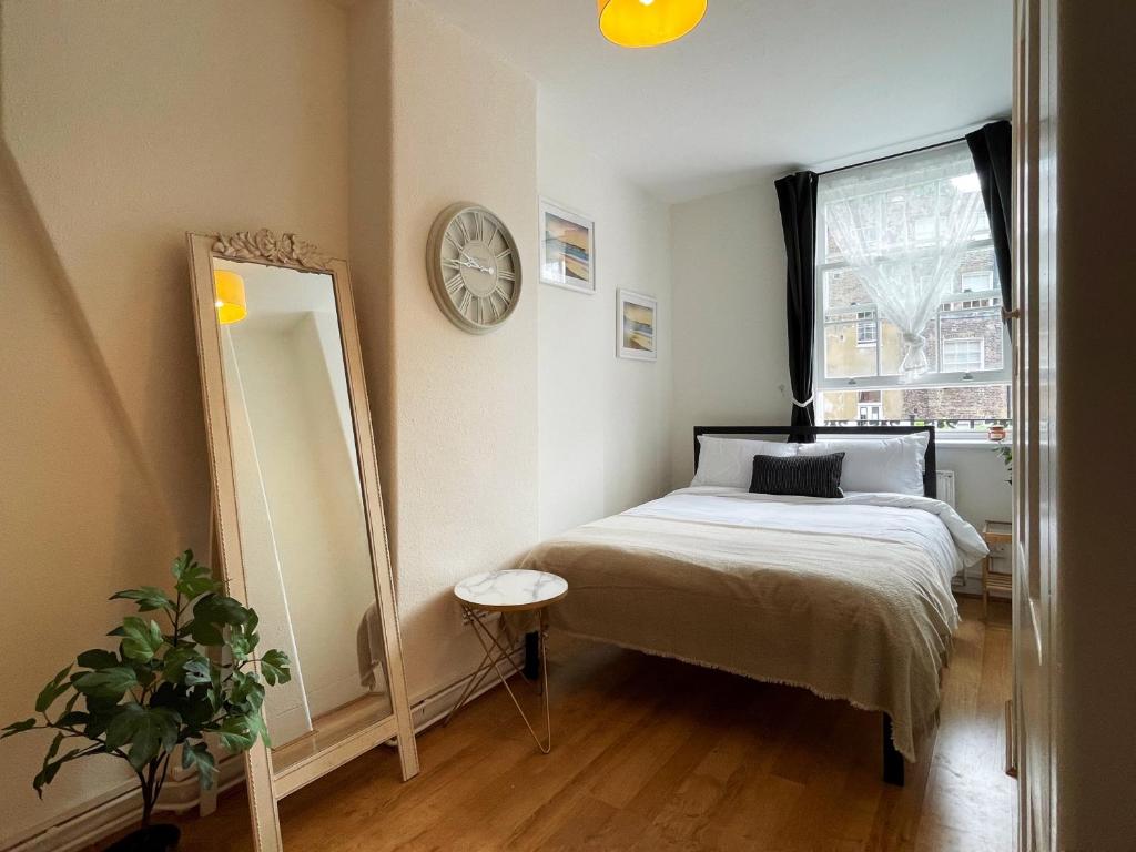 een slaapkamer met een bed, een spiegel en een klok bij Lisa's Place near Kings Cross - 2 Double Beds, 1 Sofa Bed, Great Location, Ideal for Families in Londen