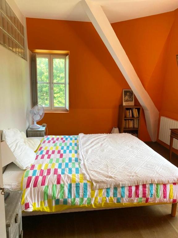 łóżko w pokoju z pomarańczową ścianą w obiekcie Manoir majestueux à Chaniers avec piscine privée w mieście Chaniers