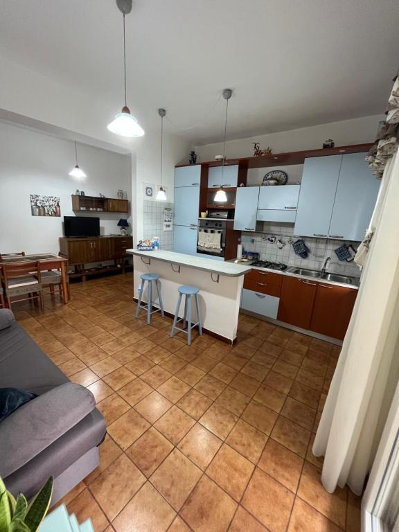 uma cozinha e sala de estar com armários brancos e piso em azulejo em Rifugio del marinaio em Milazzo