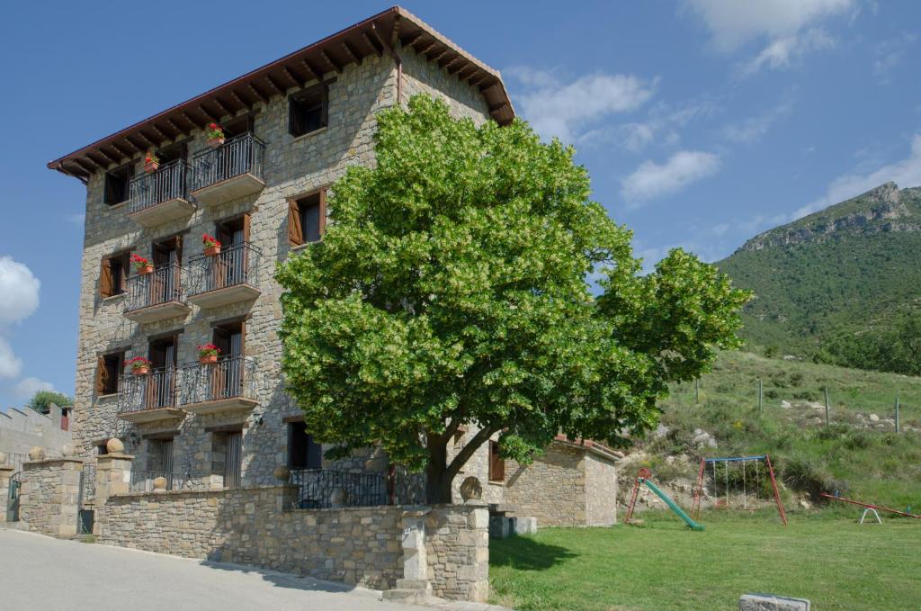 un edificio de piedra con un árbol delante de él en Casa Soltero Apartamentos, en Aguascaldas