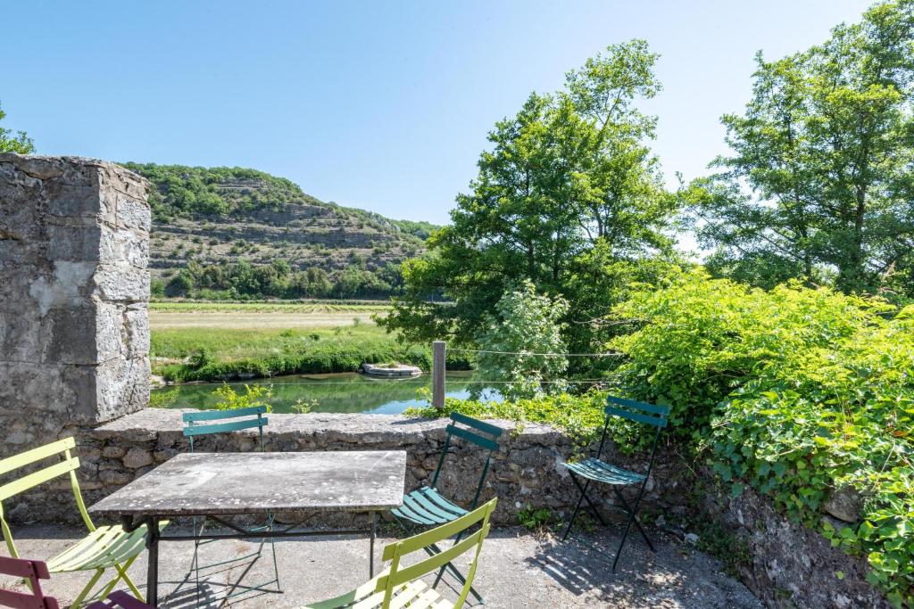 eine Terrasse mit einem Tisch und Stühlen neben einem Fluss in der Unterkunft Les Pieds dans la Beaume in Joyeuse