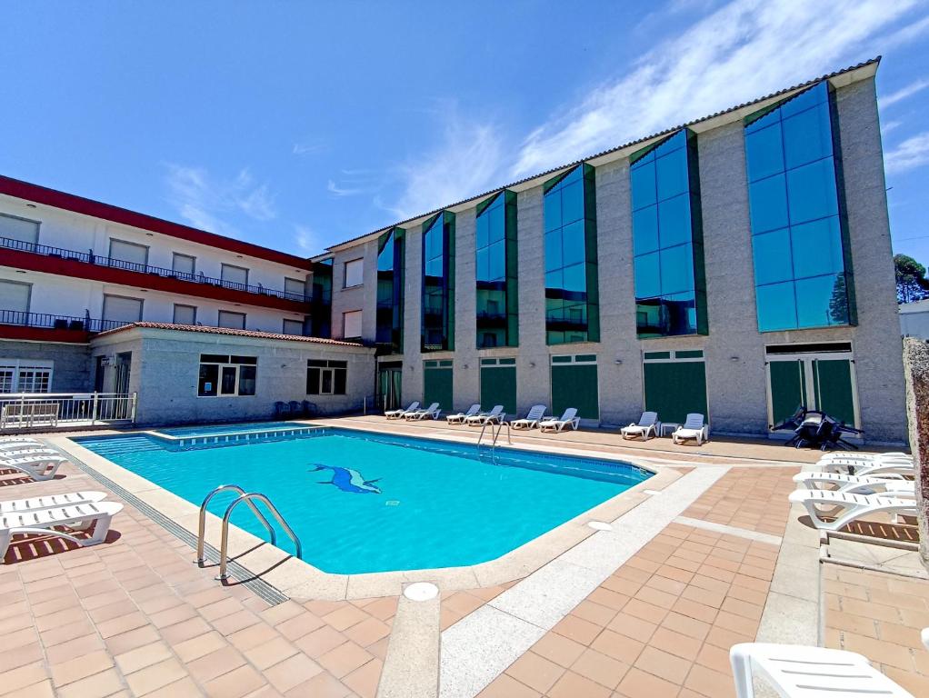 a swimming pool in front of a building at Hotel Galaico in Sanxenxo