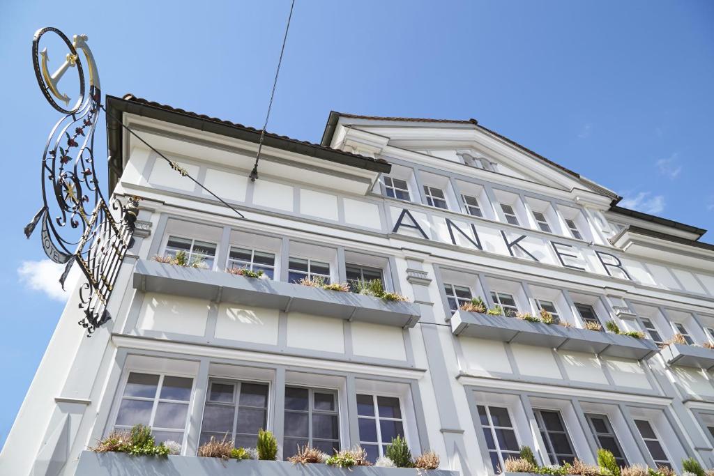 ein weißes Gebäude mit Fenstern und einem Schild darauf in der Unterkunft Anker Hotel Restaurant in Teufen