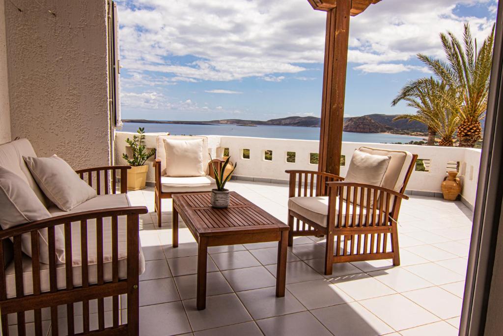 a patio with chairs and a table and a view of the water at Castri Village Hotel in Palekastron