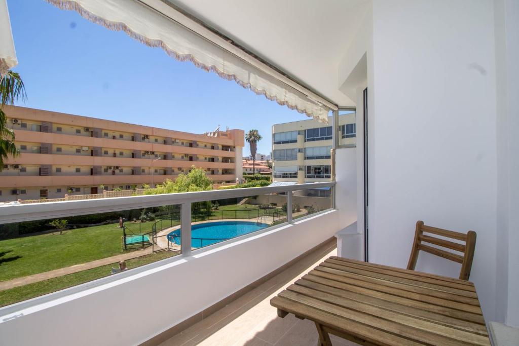 einen Balkon mit einer Holzbank und Blick auf ein Gebäude in der Unterkunft Vistamarina B 211 By IVI Real Estate in Torremolinos