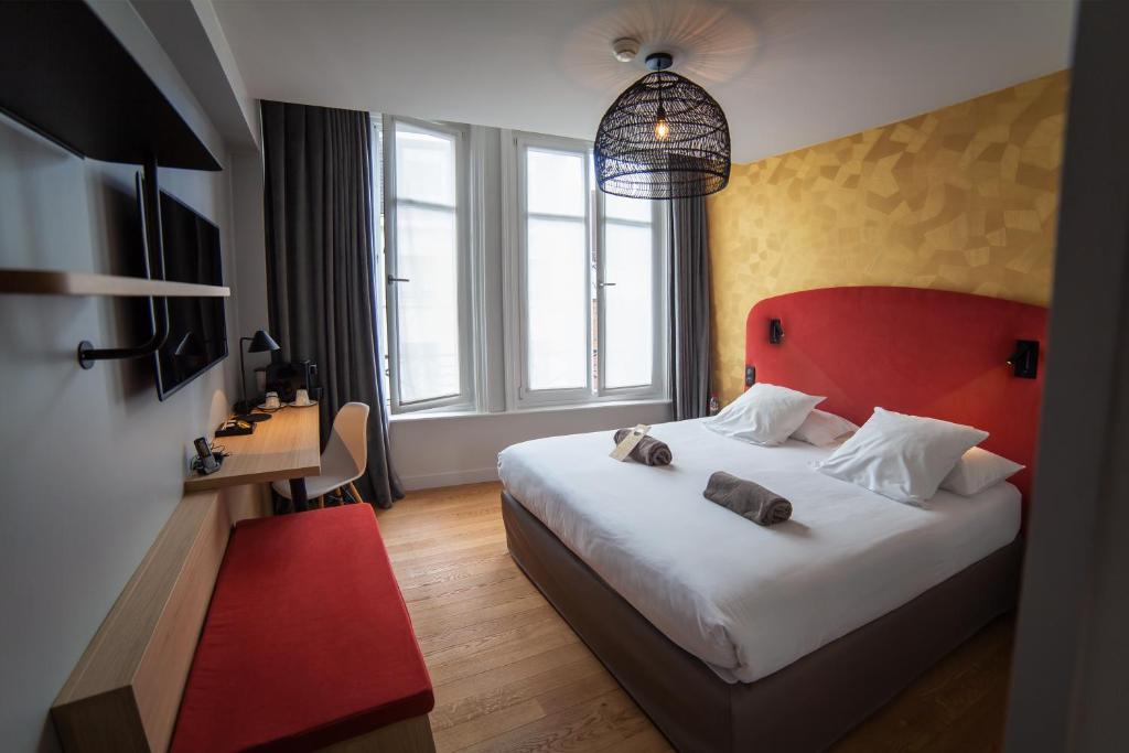 een slaapkamer met een groot bed met een rood hoofdeinde bij Hotel Kanaï in Lille