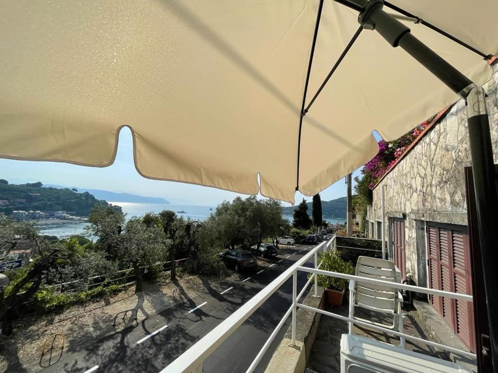 un patio con ombrellone e sedie su un balcone di Monolocale Baia dei Delfini a Portovenere