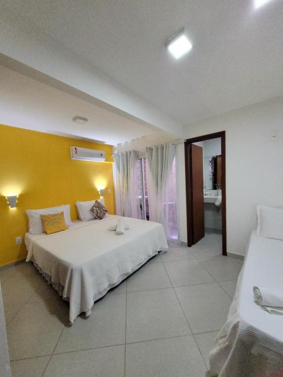 - une chambre avec un grand lit et un mur jaune dans l'établissement Apartamentos da Gaby, à Morro de São Paulo