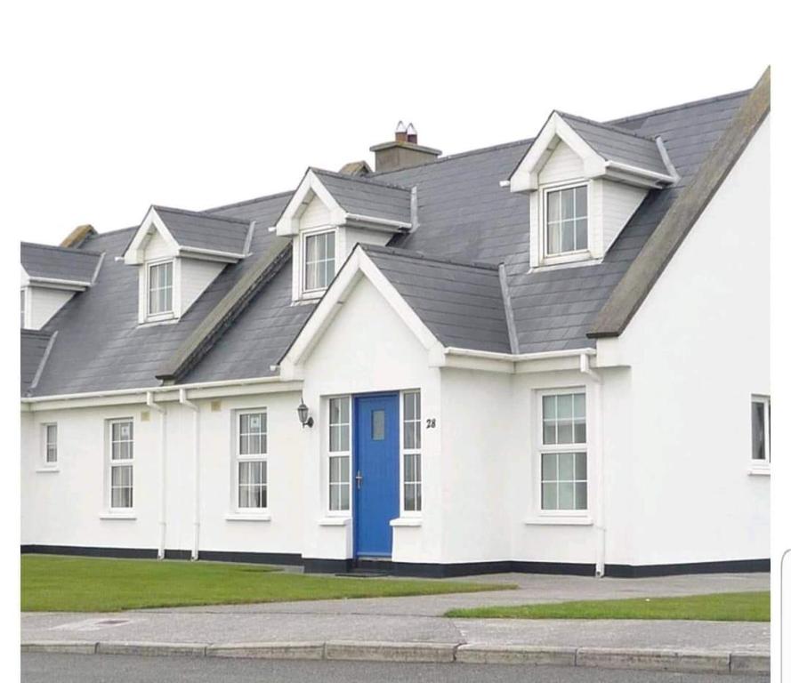 a white house with a blue door at 20 Holiday Cottage, East End Ballybunion in Ballybunion