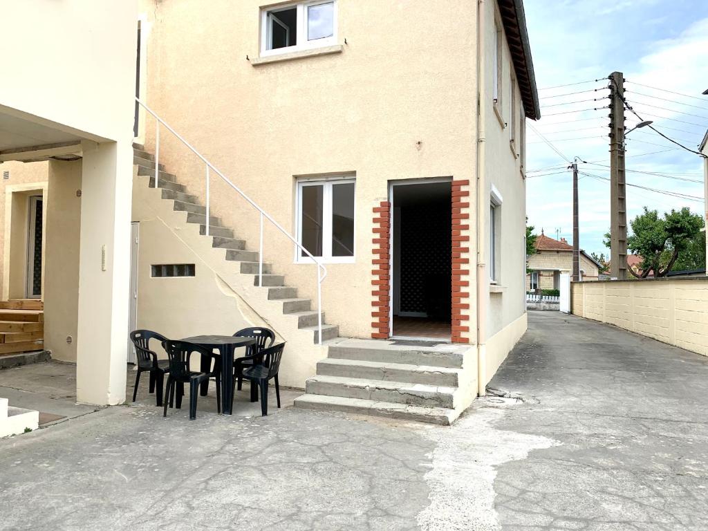 een tafel en stoelen voor een gebouw bij Comme chez soi , Déplacement Pro in Mondeville