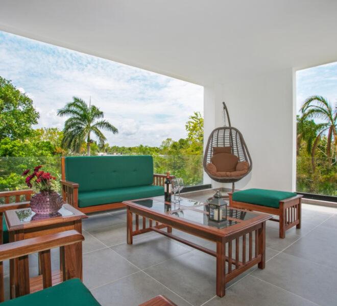 a living room with couches and tables on a balcony at Corasol Nick Price By PARR CONDOS in Playa del Carmen