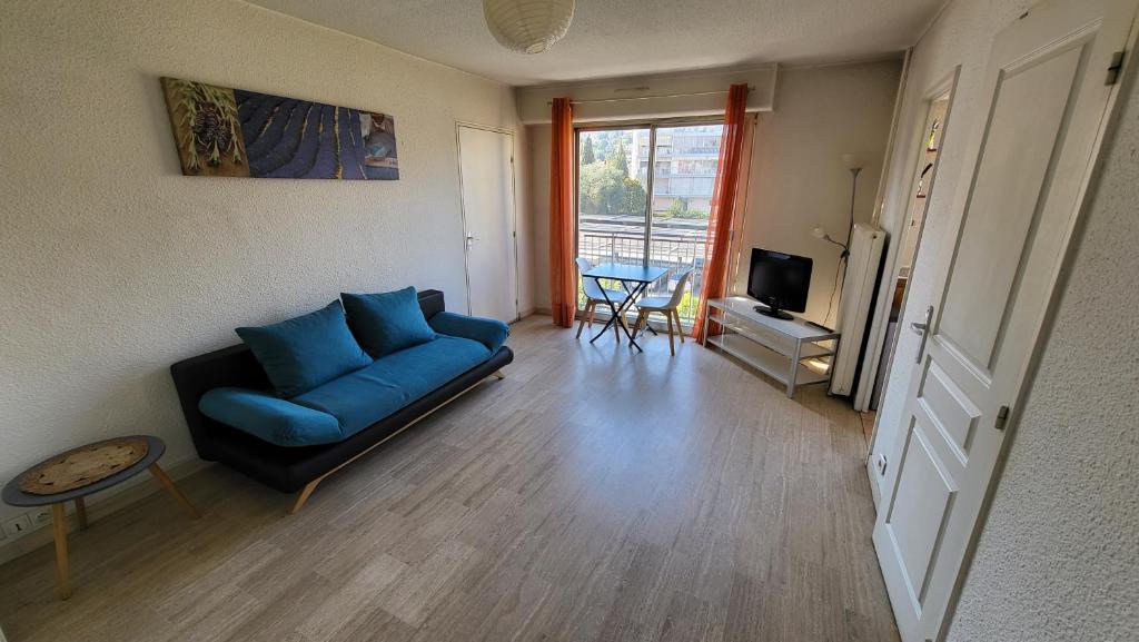 a living room with a blue couch and a television at Studio Heart of Golfe Juan in Golfe-Juan