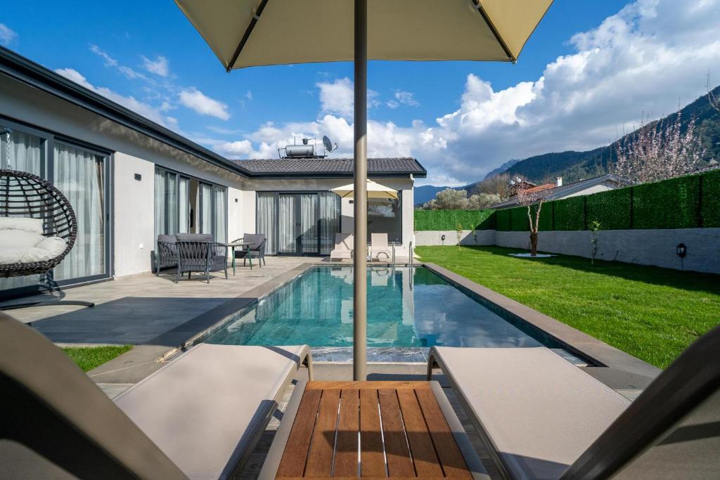 een huis met een zwembad en een parasol bij 2 Bedroom Private Villa with swimming pool in Kayakoy